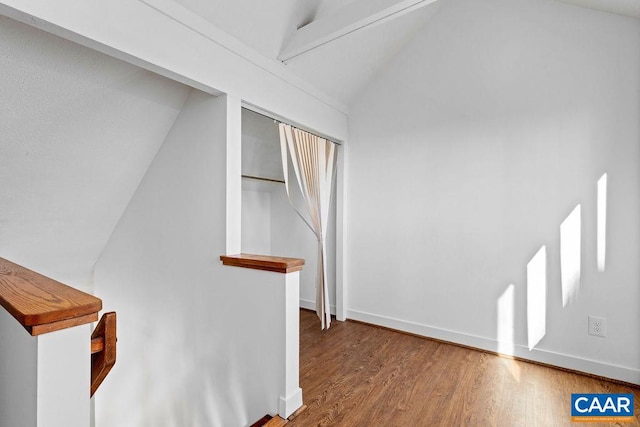 hallway with hardwood / wood-style floors and vaulted ceiling