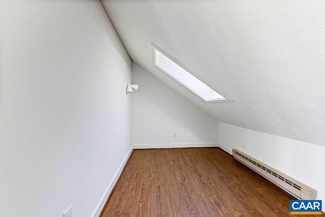 bonus room featuring a baseboard heating unit, a textured ceiling, hardwood / wood-style flooring, and vaulted ceiling with skylight