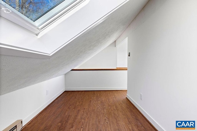 additional living space with wood-type flooring and lofted ceiling with skylight