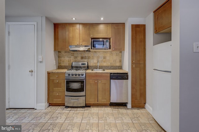 kitchen featuring light stone counters, sink, appliances with stainless steel finishes, and tasteful backsplash