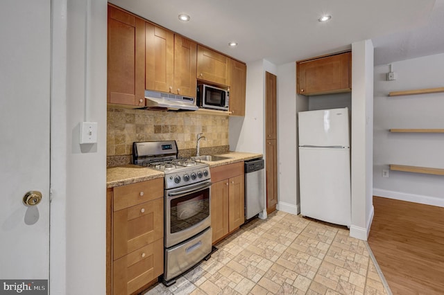 kitchen with tasteful backsplash, sink, stainless steel appliances, and light wood-type flooring