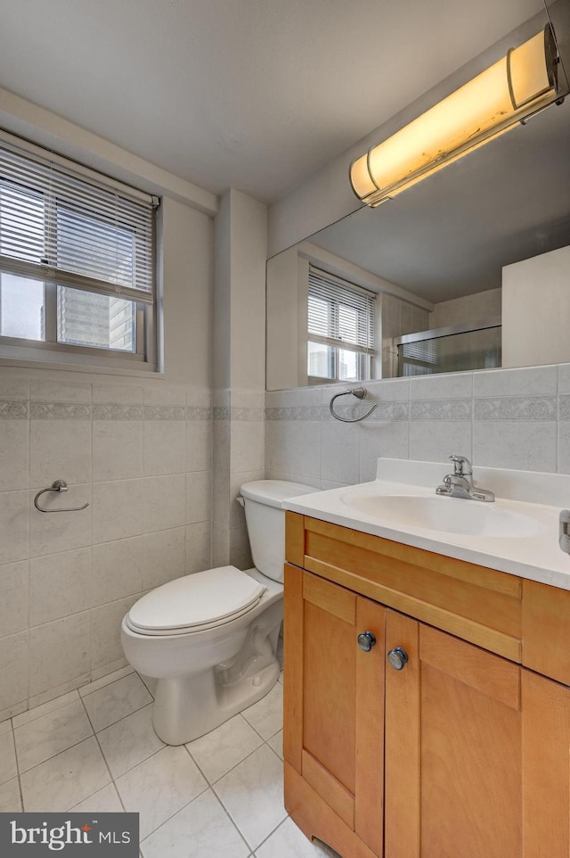 bathroom with walk in shower, vanity, tile patterned floors, and tile walls