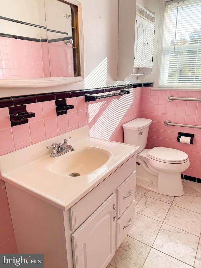 bathroom featuring tile patterned floors, vanity, toilet, and tile walls