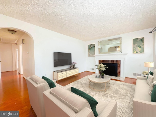 living room with hardwood / wood-style floors, a fireplace, and a textured ceiling