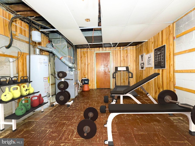 workout area with heating unit, water heater, and wooden walls