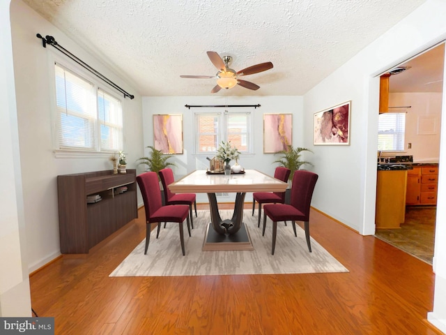 dining room with ceiling fan, light wood-type flooring, and a textured ceiling