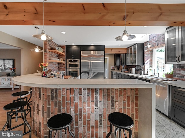 kitchen featuring stainless steel appliances, a breakfast bar, and decorative light fixtures