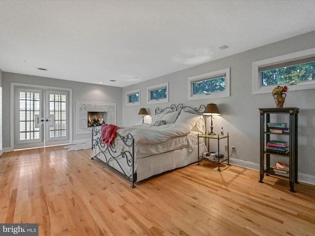 bedroom with multiple windows, light wood-type flooring, and access to outside