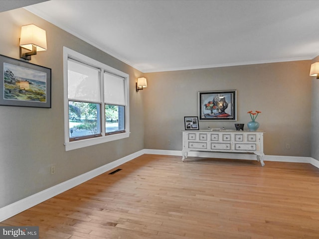 empty room with light hardwood / wood-style floors and crown molding