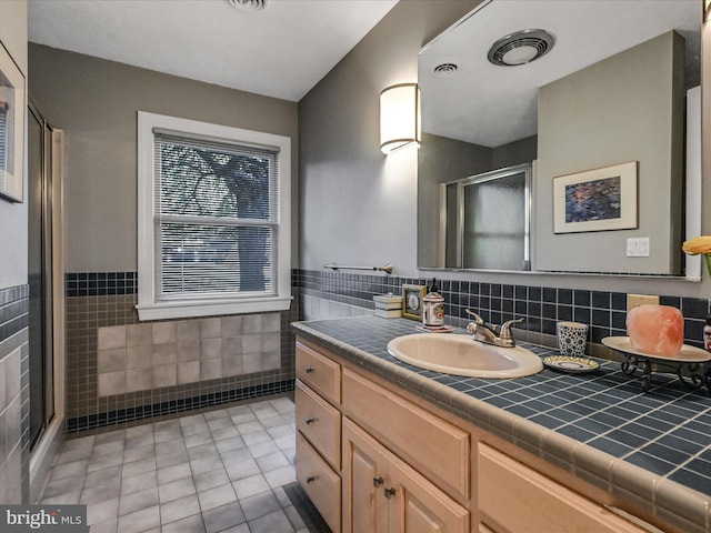 bathroom featuring vanity, tile patterned floors, an enclosed shower, and tile walls