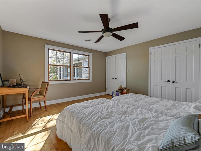 bedroom with two closets, ceiling fan, and light hardwood / wood-style flooring