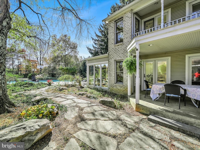 view of patio / terrace featuring a balcony and a pool