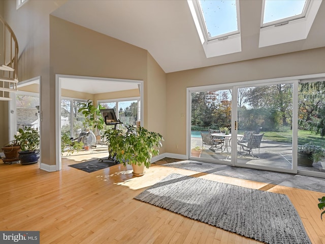 doorway to outside with a wealth of natural light, hardwood / wood-style flooring, and vaulted ceiling with skylight