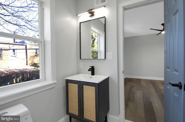 bathroom with ceiling fan, vanity, wood-type flooring, and toilet