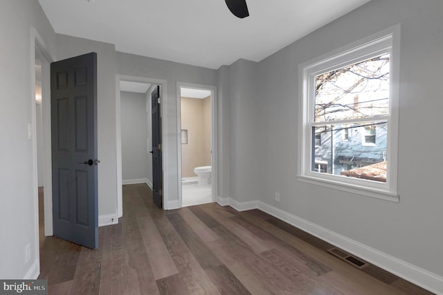 unfurnished bedroom featuring ensuite bathroom, dark hardwood / wood-style floors, and ceiling fan