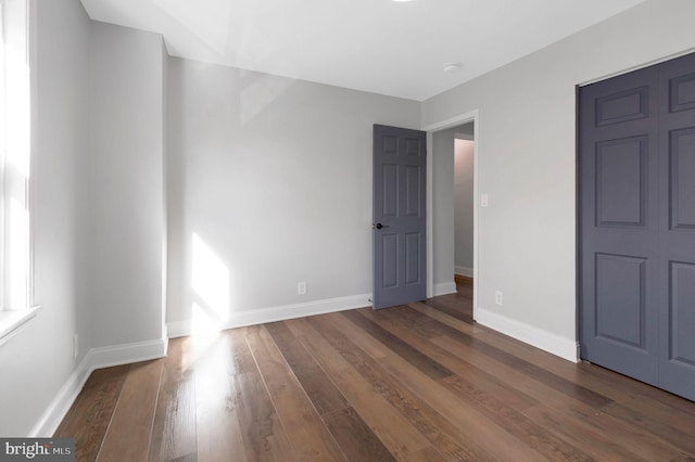 unfurnished bedroom with a closet and dark wood-type flooring