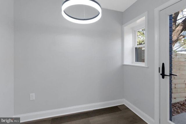 empty room featuring a healthy amount of sunlight and dark wood-type flooring