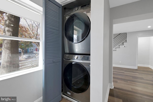 laundry room featuring stacked washer / dryer and dark hardwood / wood-style floors