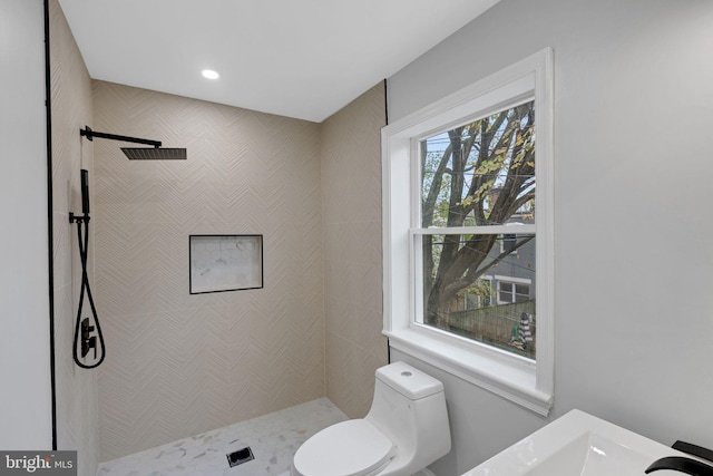 bathroom featuring a shower, toilet, and plenty of natural light