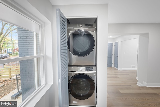 washroom featuring light hardwood / wood-style floors and stacked washer and dryer