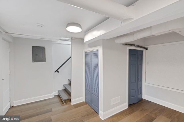 basement with electric panel, a barn door, and hardwood / wood-style flooring