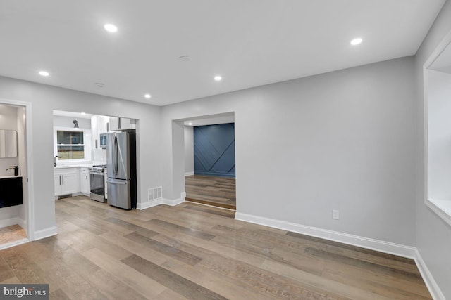 unfurnished living room featuring a barn door and light hardwood / wood-style floors