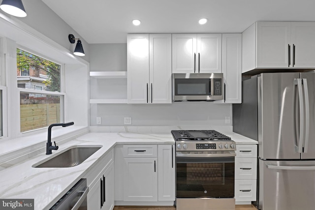 kitchen with light stone counters, white cabinetry, sink, and appliances with stainless steel finishes