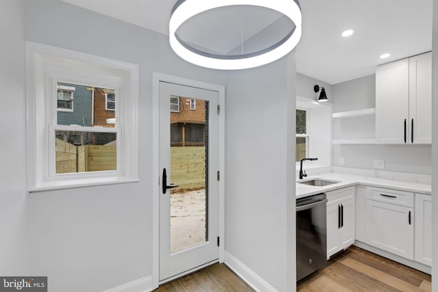 kitchen with white cabinetry, dishwasher, light hardwood / wood-style floors, and sink