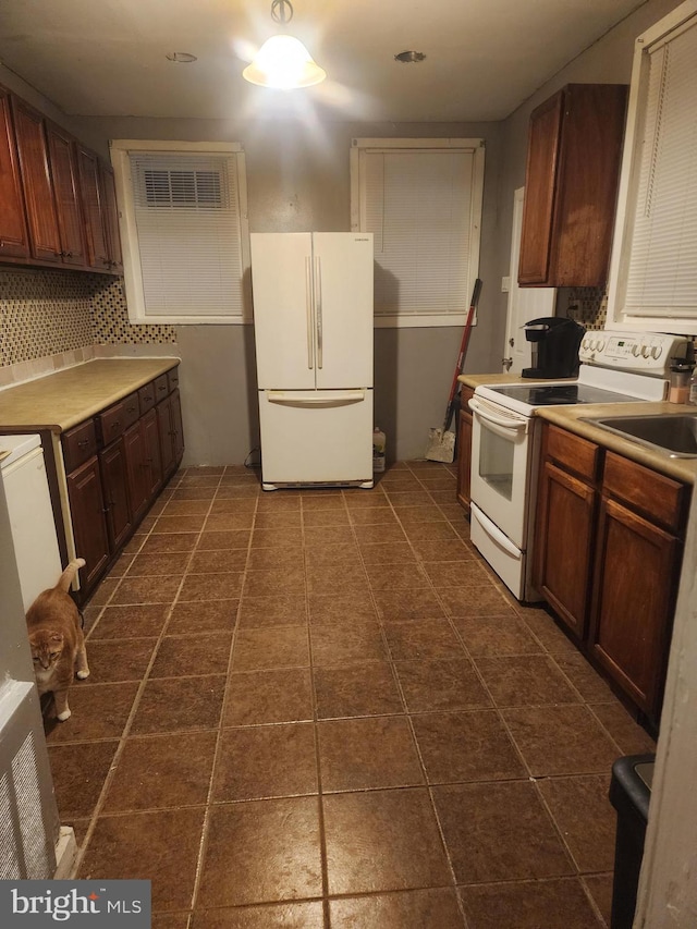 kitchen with tasteful backsplash, white appliances, and sink