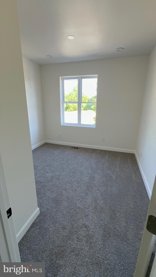 spare room with dark colored carpet