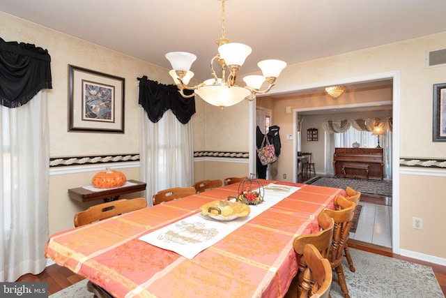 dining space featuring hardwood / wood-style floors and a chandelier