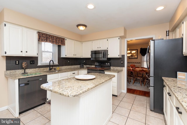 kitchen featuring light stone counters, sink, black appliances, white cabinets, and a center island