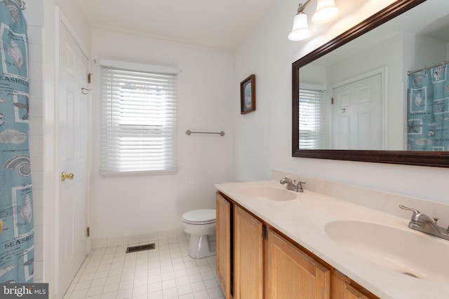 bathroom with toilet, vanity, and tile patterned floors