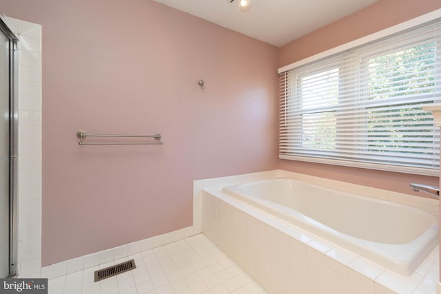 bathroom featuring tile patterned flooring and a relaxing tiled tub