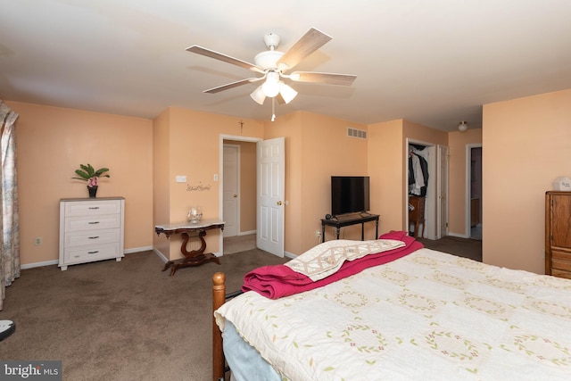 bedroom featuring a closet, a spacious closet, dark carpet, and ceiling fan