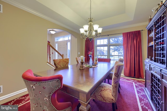 carpeted dining area with a chandelier, a tray ceiling, and crown molding