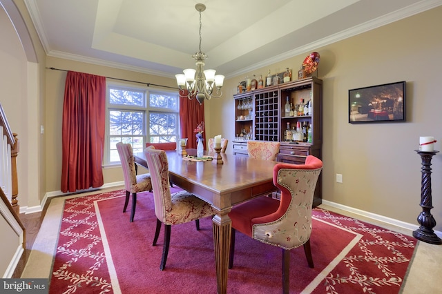 dining space with a tray ceiling, a notable chandelier, and ornamental molding