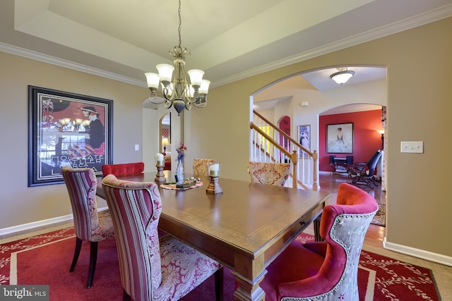 dining room with a raised ceiling, crown molding, and a notable chandelier