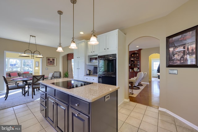 kitchen with black appliances, light tile patterned floors, hanging light fixtures, a center island, and white cabinets