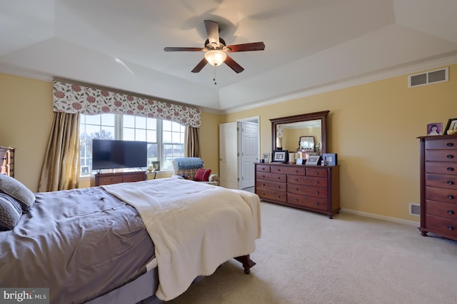 bedroom with a tray ceiling, light colored carpet, ceiling fan, and crown molding