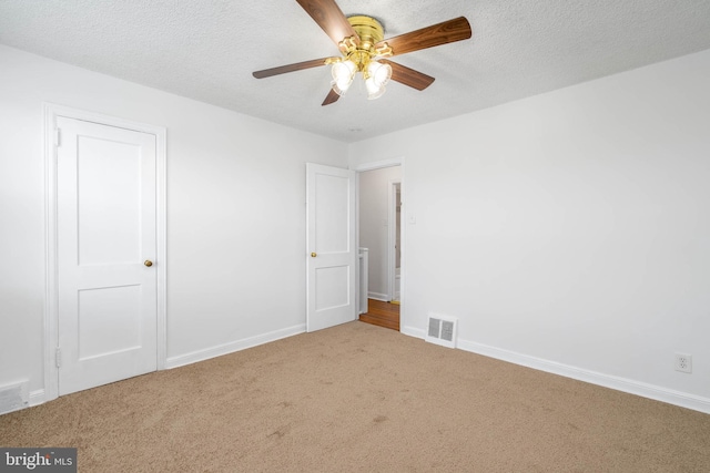 carpeted spare room featuring ceiling fan and a textured ceiling