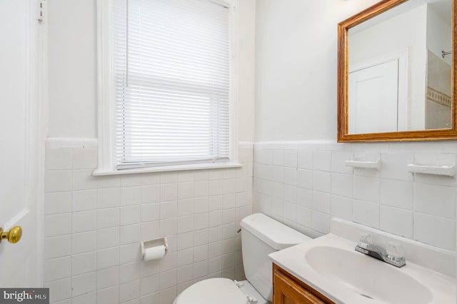 bathroom featuring vanity, tile walls, and toilet