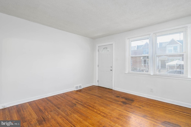 spare room featuring wood-type flooring and a textured ceiling