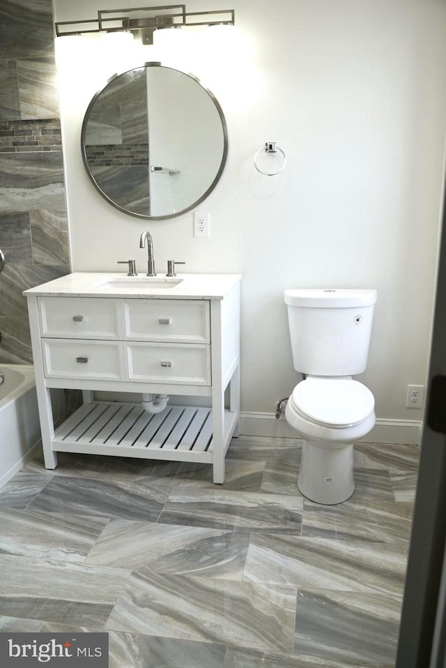 bathroom featuring toilet, a tub to relax in, and vanity