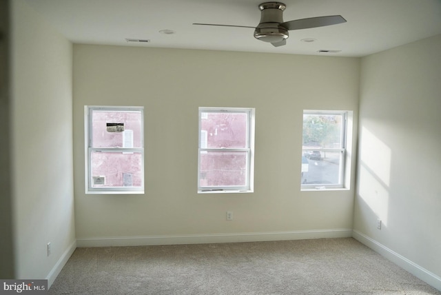 carpeted spare room featuring ceiling fan and plenty of natural light