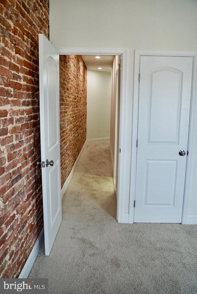 corridor featuring brick wall and light carpet