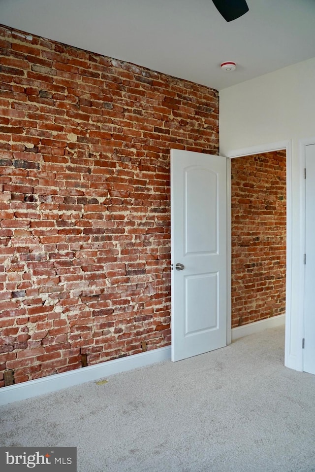 empty room featuring carpet floors and brick wall