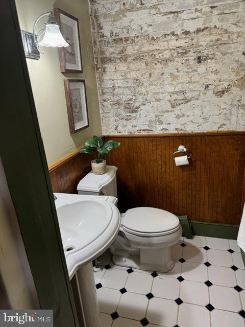 bathroom with toilet and wood walls