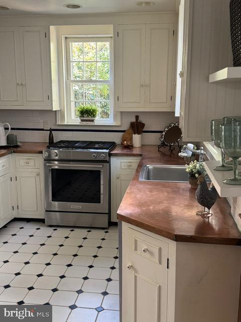 28 The Strand, New Castle, DE 19720 - kitchen with stainless steel range with gas cooktop, wooden counters, a sink, and white cabinets