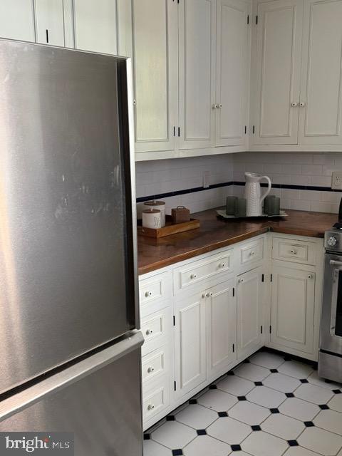 28 The Strand, New Castle, DE 19720 - kitchen with stainless steel appliances, wooden counters, decorative backsplash, and white cabinetry